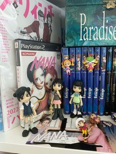 some anime figurines are sitting on a shelf next to books and dvds in a store