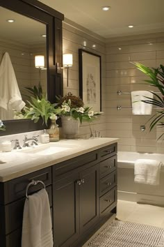 a bathroom with two sinks and a bathtub next to a plant in a vase