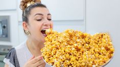 a woman holding a bowl full of popcorn in her hand and making a funny face