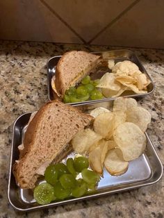 two trays with sandwiches and chips on them