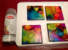 four square coasters sitting on top of a table next to a can of paint