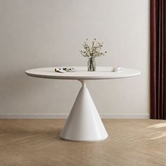 a white table sitting on top of a wooden floor next to a vase with flowers