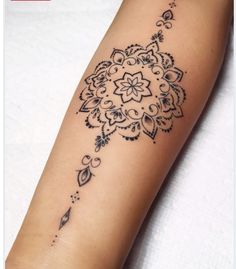 a woman's arm with a black and white tattoo design on the left forearm