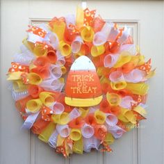 a trick or treat mesh wreath with an orange and white hat on the front door