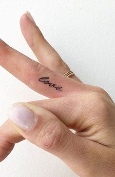 a person's hand with a small tattoo on it and the word love written in cursive font