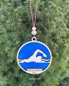 a blue and white ornament hanging from a pine tree with the name benjamin on it