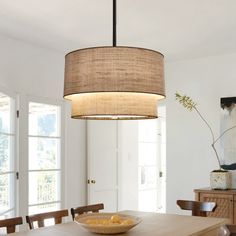 a dining room table with a bowl of fruit on it and a lamp hanging from the ceiling