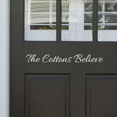 a black front door with the words the cottons believe on it's side