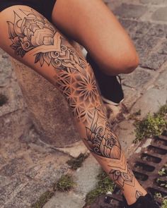 a woman's legs with tattoos on them and flowers in the middle of her leg