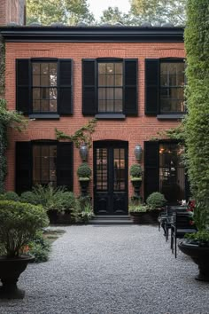 a brick house with black shutters and potted plants