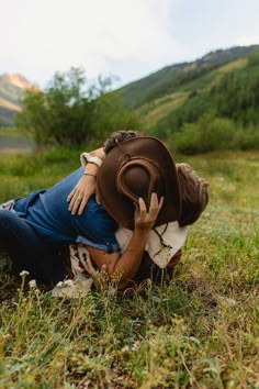 a woman wearing a cowboy hat laying on the ground with her hands behind her head