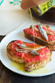 toasted bread with red sauce and fish on it being drizzled over