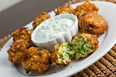 a white plate topped with fried food next to a bowl of dip