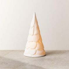 a white ceramic christmas tree sitting on top of a marble table next to a wall