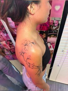 a woman with a flower tattoo on her arm and shoulder, standing in front of a mirror