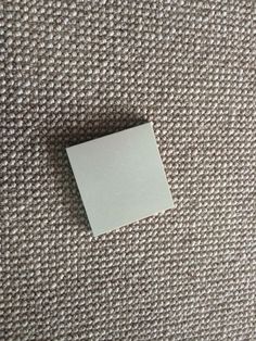 a piece of white paper sitting on top of a gray carpet covered in lots of tiny dots