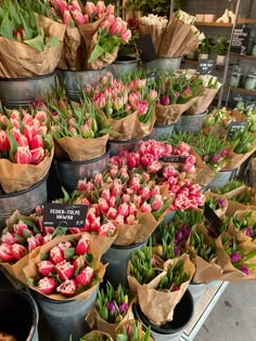 several buckets filled with pink and red tulips on display at a flower shop