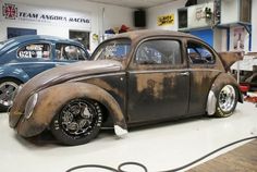 an old vw bug sitting on top of a hard wood floor in a garage