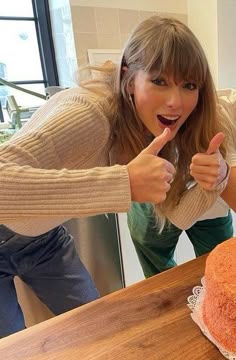 a woman pointing at a cake on a table