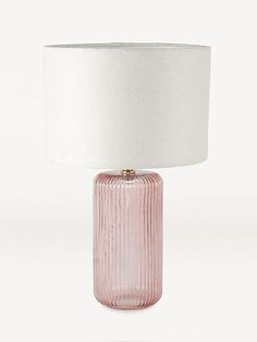 a pink glass table lamp with a white shade on the base and a light bulb attached to it