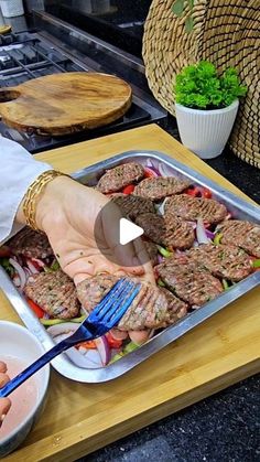 a person holding a fork over a pan filled with food