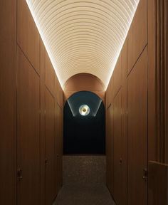 an empty hallway with wooden walls and ceiling lights on either side of the corridor is lit by recessed lighting