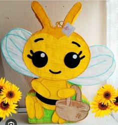 a paper cut out of a bee holding a basket with sunflowers around it