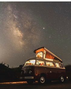 an old van parked under the stars in the night sky with its roof open and lights on