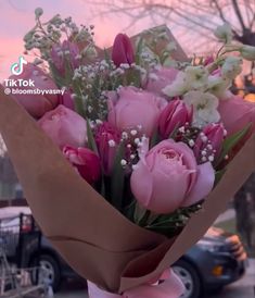 a bouquet of pink roses wrapped in brown paper with baby's breath on the side