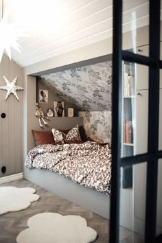 a bed sitting under a window next to a white star shaped light above it's headboard