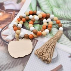 the wooden beaded bracelet with tassel is next to an orange, white and brown necklace