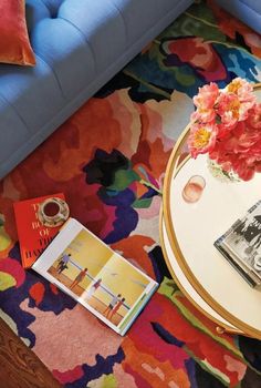 a living room with a blue couch, coffee table and flowers on the rugs