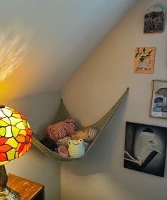 a hammock hanging from the side of a wall next to a lamp and pictures