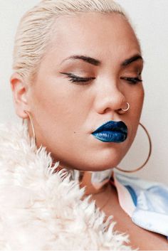 a woman with blue lipstick and hoop earrings