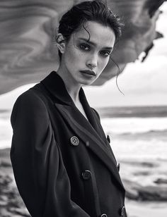 black and white photograph of a woman standing on the beach with her hands in her pockets