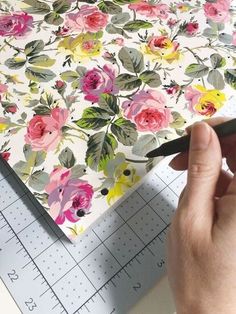 a person is cutting out flowers on a piece of paper with a ruler next to it