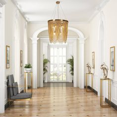 an elegant hallway with chandelier, chairs and paintings on the wall in front of it