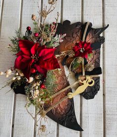 a masquerade with red flowers and greenery on the side, sitting on a wooden surface