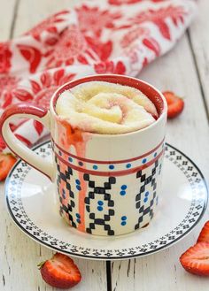 a cup filled with liquid sitting on top of a white and blue plate next to tomatoes