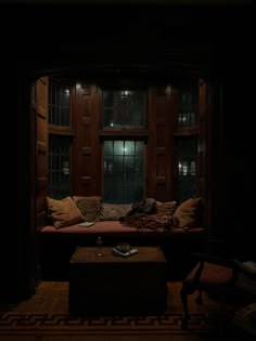 a living room filled with lots of furniture in front of a large window at night