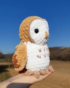 a small stuffed owl sitting on someone's hand