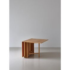 a small wooden table sitting on top of a white floor next to a gray wall