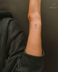 a person with a cross tattoo on their arm