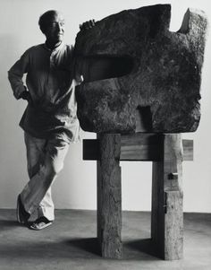 a man standing next to a large rock