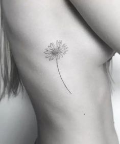 a black and white photo of a woman's back with a dandelion tattoo