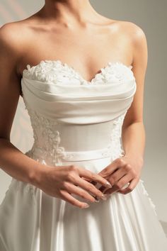 a woman in a white wedding dress is holding her hands together