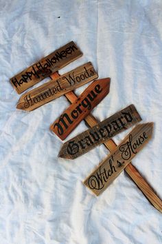 four wooden signs that are on top of a white sheet and one is pointing to different words