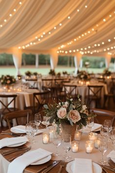 the tables are set with white linens and candles for an elegant wedding reception in a marquee