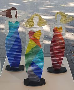 three colorful vases sitting on top of a white table next to each other in front of a tree