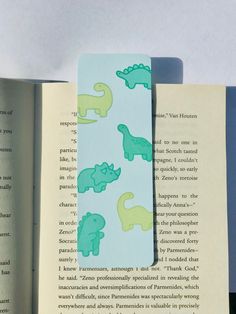 an open book with green and blue dinosaurs on it